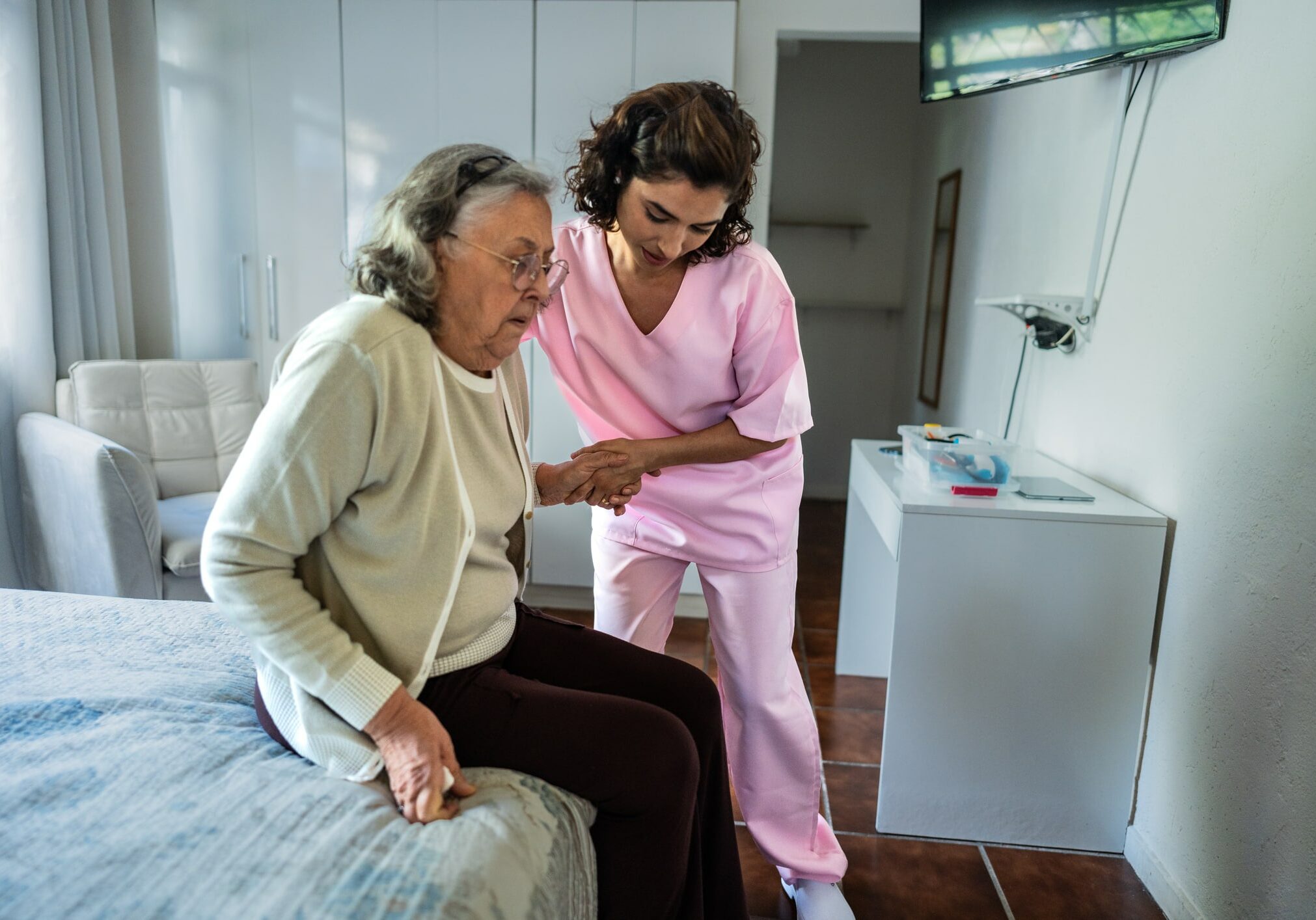 Nurse helping a senior woman sitting in bed at nursing home Nurse helping a senior woman sitting in bed at home